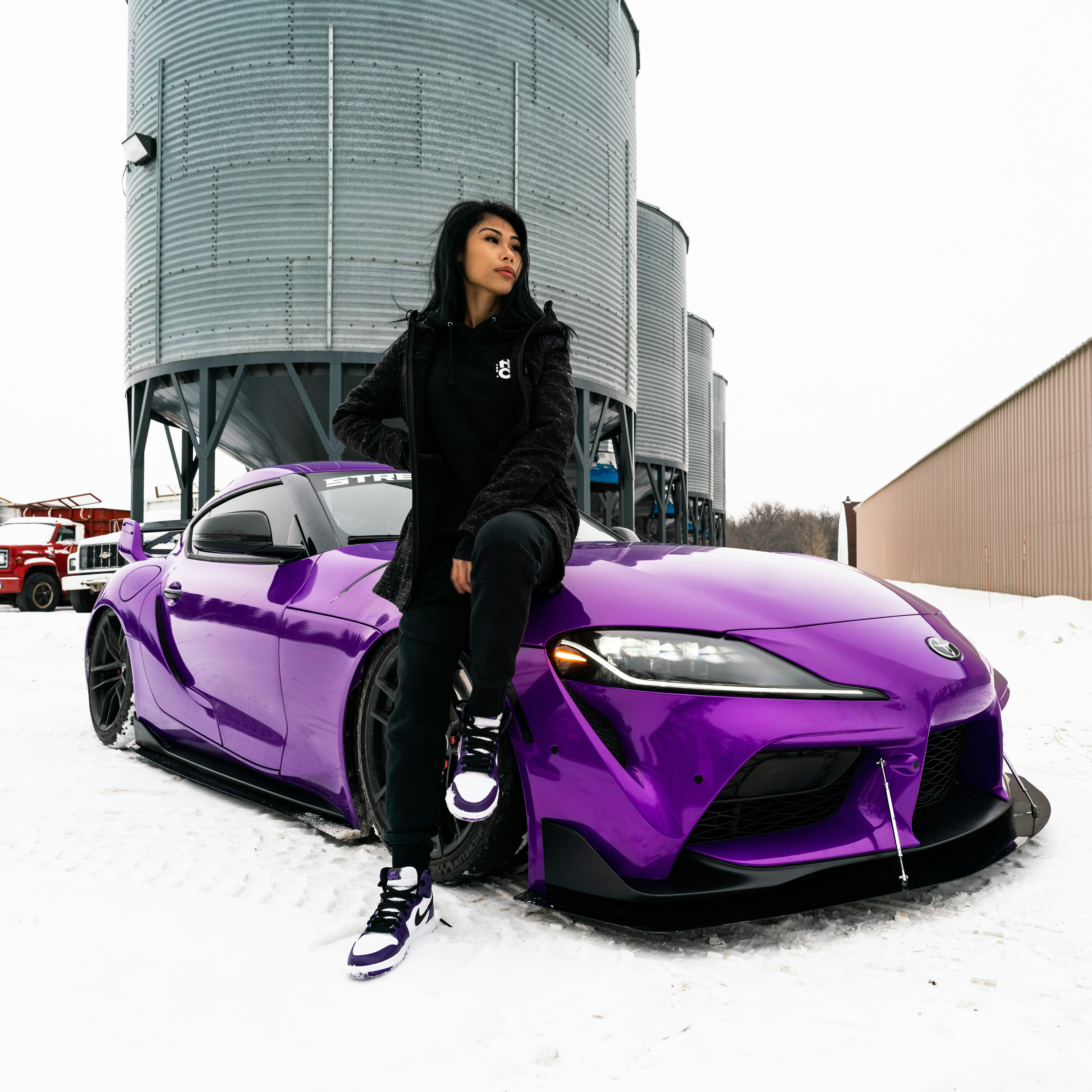 woman in black jacket and black pants standing beside purple car